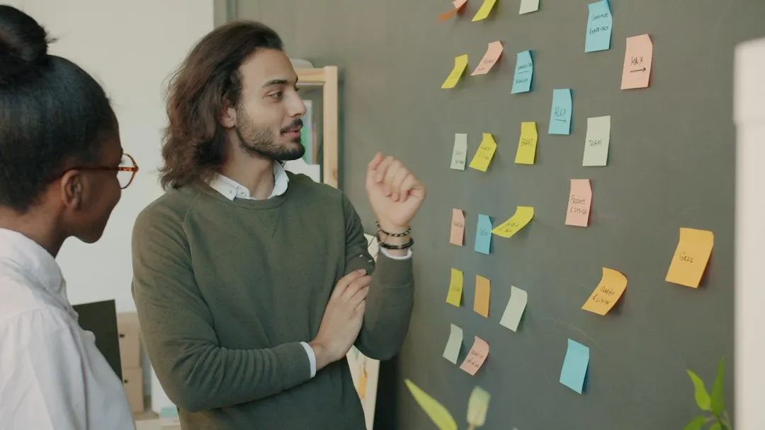 Pessoa apontando para um mapa de processo feito com post-its na parede
