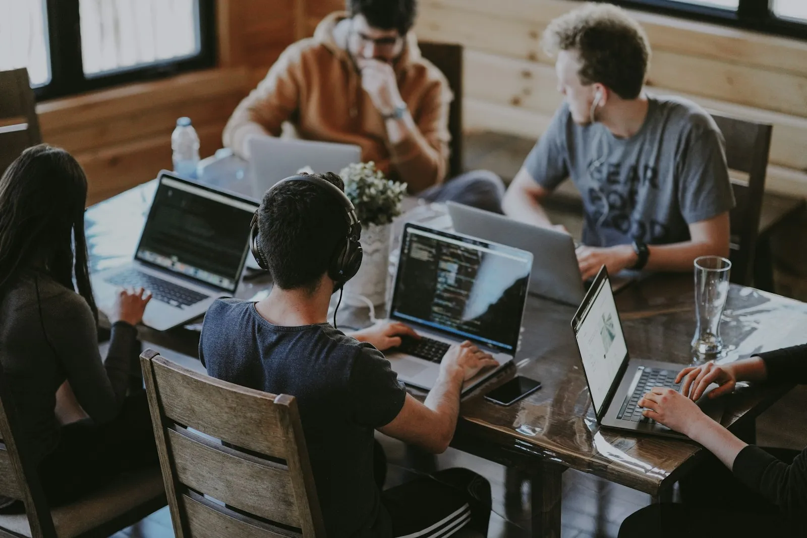 Equipe trabalhando em notebooks ao redor de uma mesa de madeira